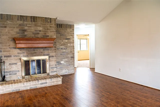 a view of empty room with wooden floor and fireplace