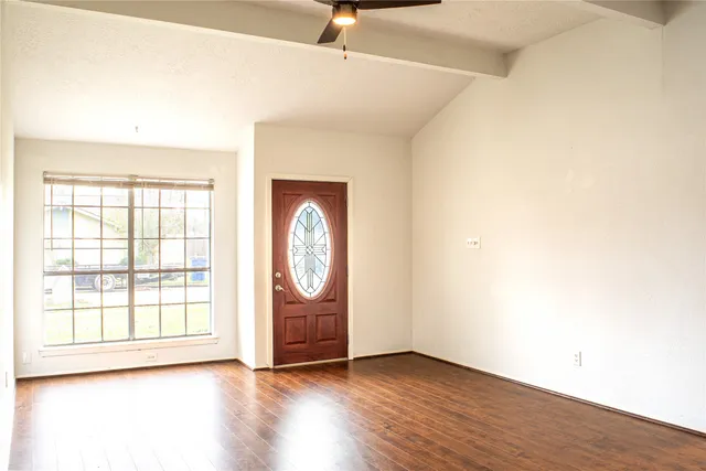 an empty room with wooden floor and windows
