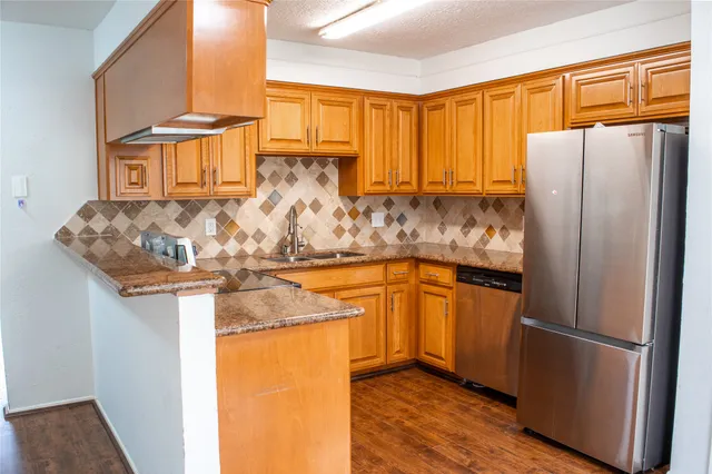 a kitchen with stainless steel appliances granite countertop a refrigerator a sink and a stove