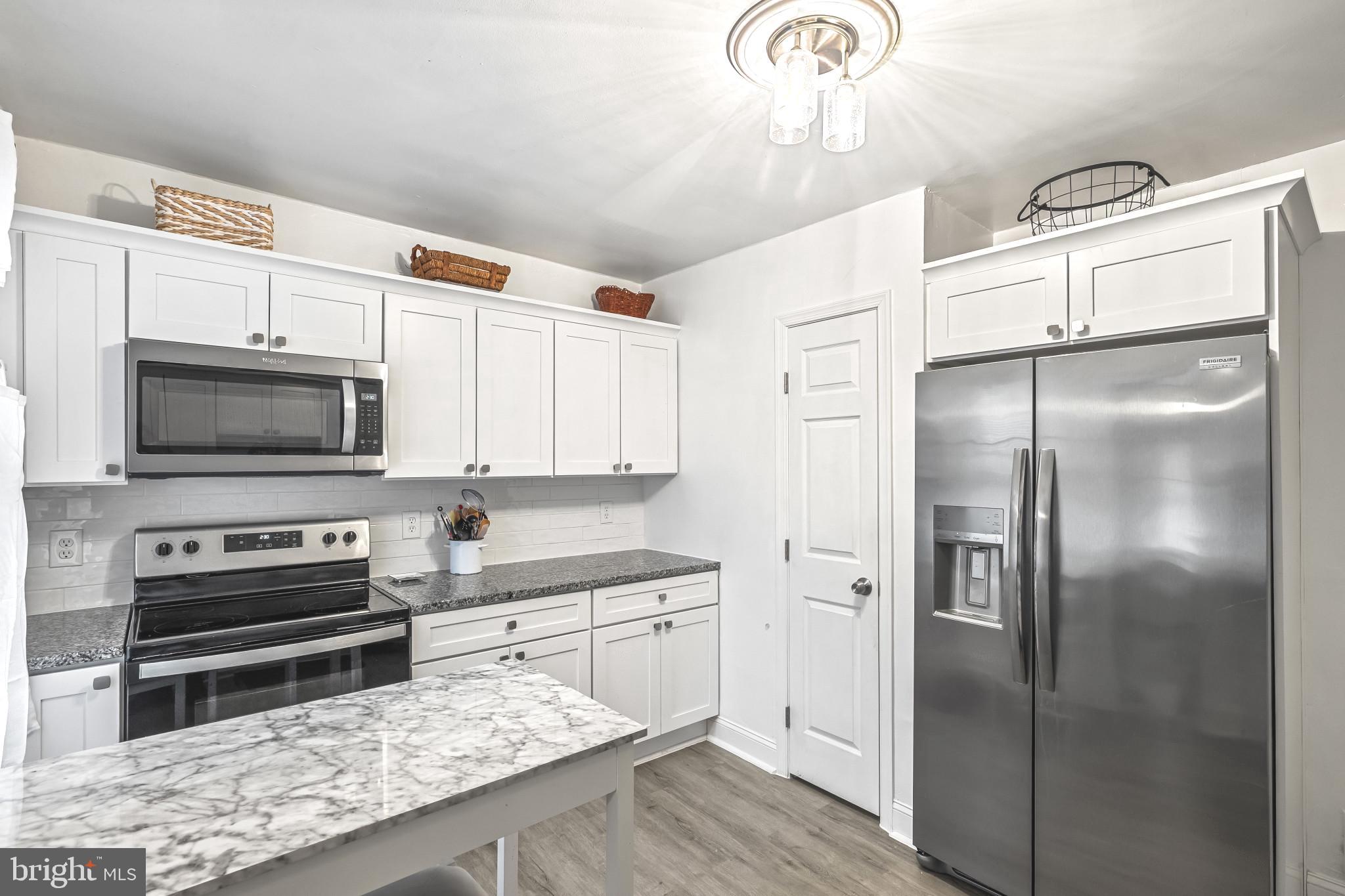 8362 Oakleigh Road Parkville, MD 21234 - Photo 7 of 28 a kitchen with stainless steel appliances granite countertop a refrigerator a stove and a microwave oven
