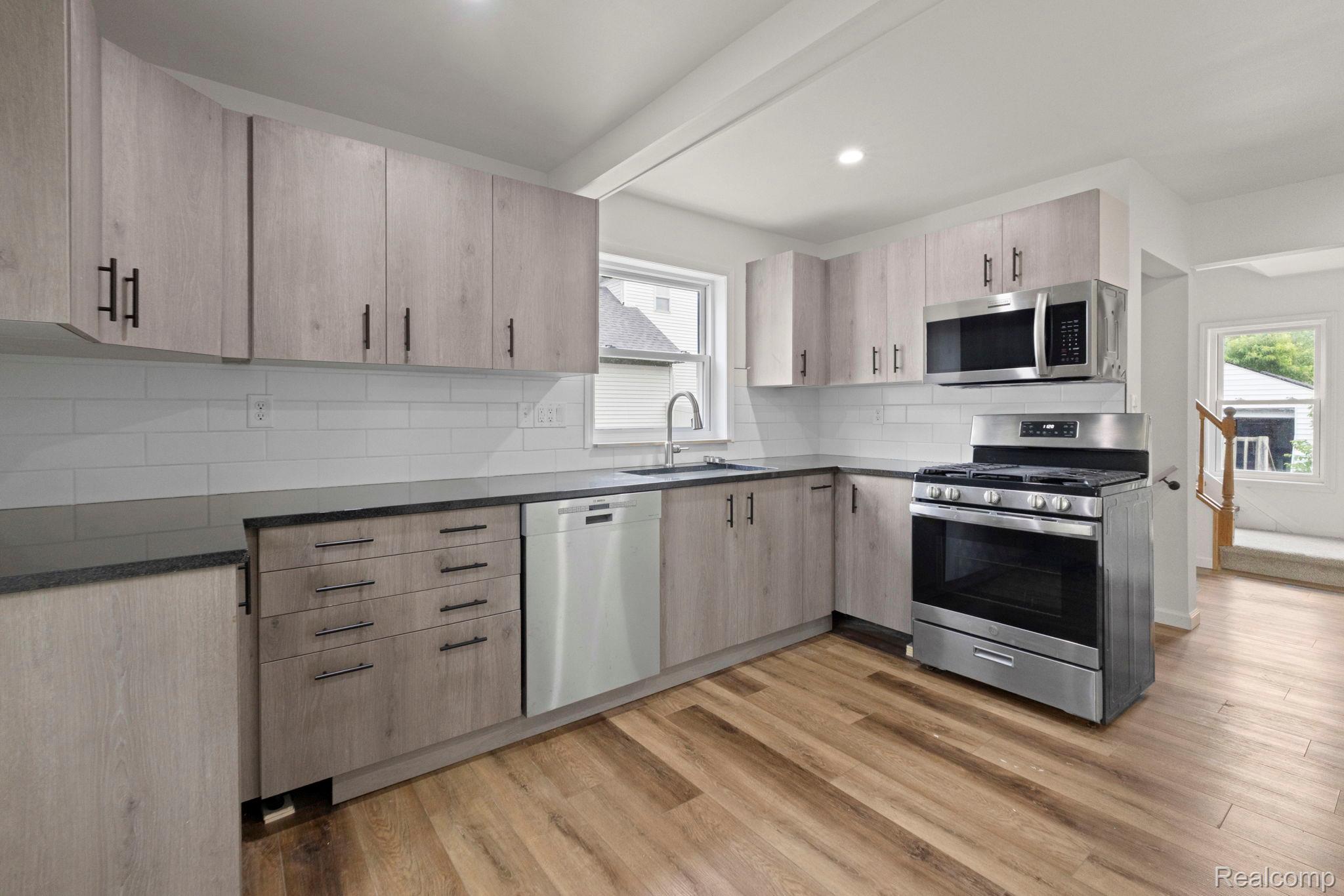 2891 Culbertson Avenue Rochester, MI 48307 - Photo 8 of 27 Contemporary kitchen featuring light wood-finish cabinetry with matte black hardware, dark countertops, and a white subway tile backsplash