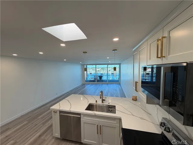 a kitchen with a sink a counter top space stainless steel appliances and cabinets