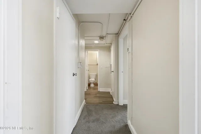 an empty room with a chandelier fan and wooden floor