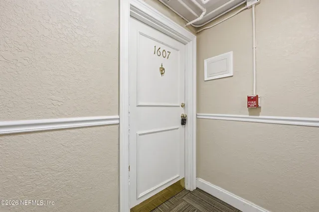 an empty room with chandelier fan and windows