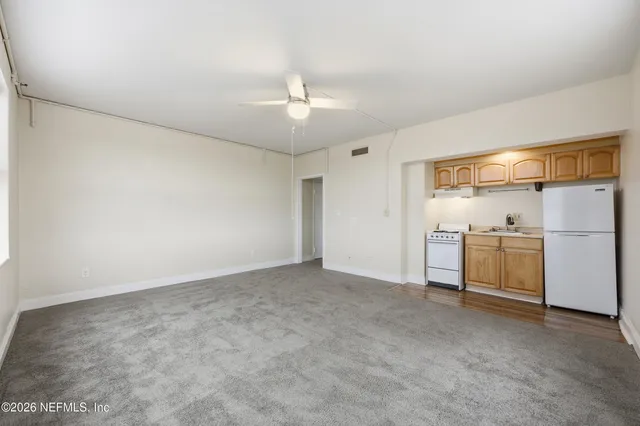 an empty room with chandelier fan and windows