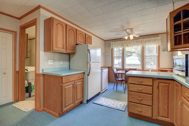 a kitchen with stainless steel appliances granite countertop a refrigerator a sink dishwasher a stove and a dining table with wooden cabinet