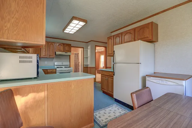 a kitchen with refrigerator and wooden floor