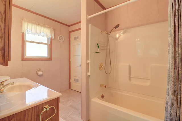 a bathroom with a granite countertop sink a mirror and a bathtub