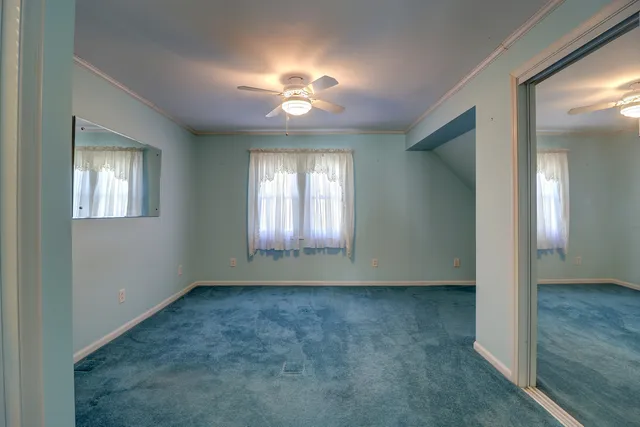 an empty room with chandelier fan and windows