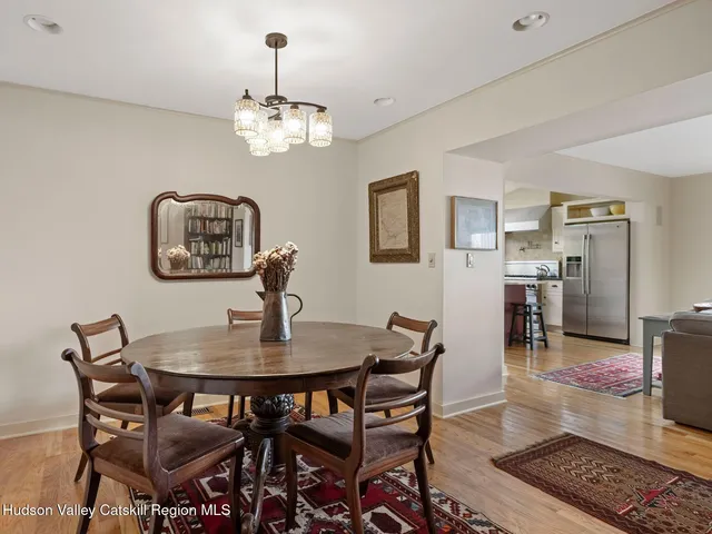 a dining room with wooden floor a chandelier a wooden table and chairs