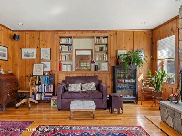 a living room with furniture large window and wooden floor