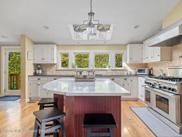 a kitchen with stainless steel appliances granite countertop a stove a sink dishwasher a microwave oven and a dining table with wooden floor