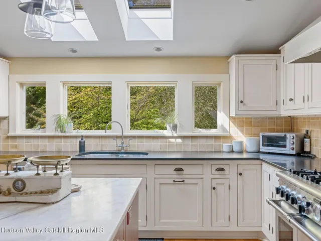 a kitchen with stainless steel appliances granite countertop a stove a sink and a granite counter tops with white cabinets