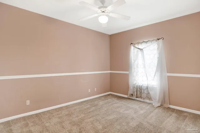 an empty room with a window and ceiling fan