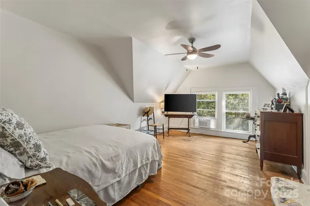 a spacious bedroom with a bed a chair a flat screen tv and a large window