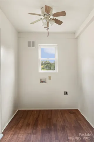 an empty room with wooden floor ceiling fan and windows