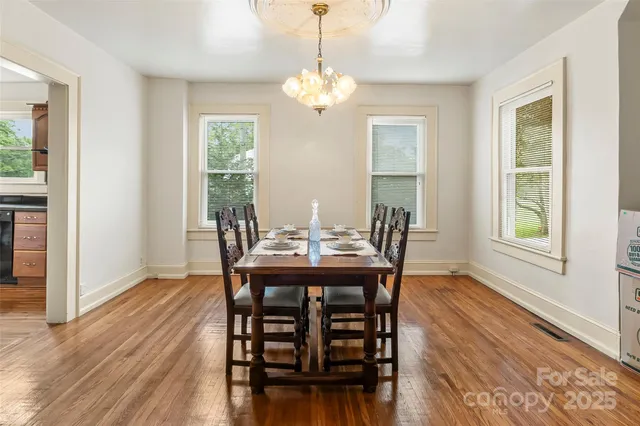 a dining room with furniture wooden floor a potted plant and a chandelier