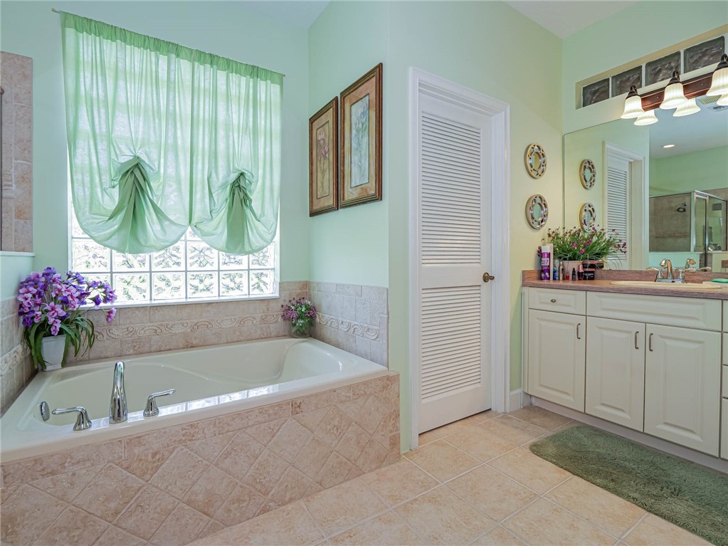 5824 Pine Ridge Circle Vero Beach, FL 32967 - Photo 19 of 34 a bathroom with a tub sink and mirror
