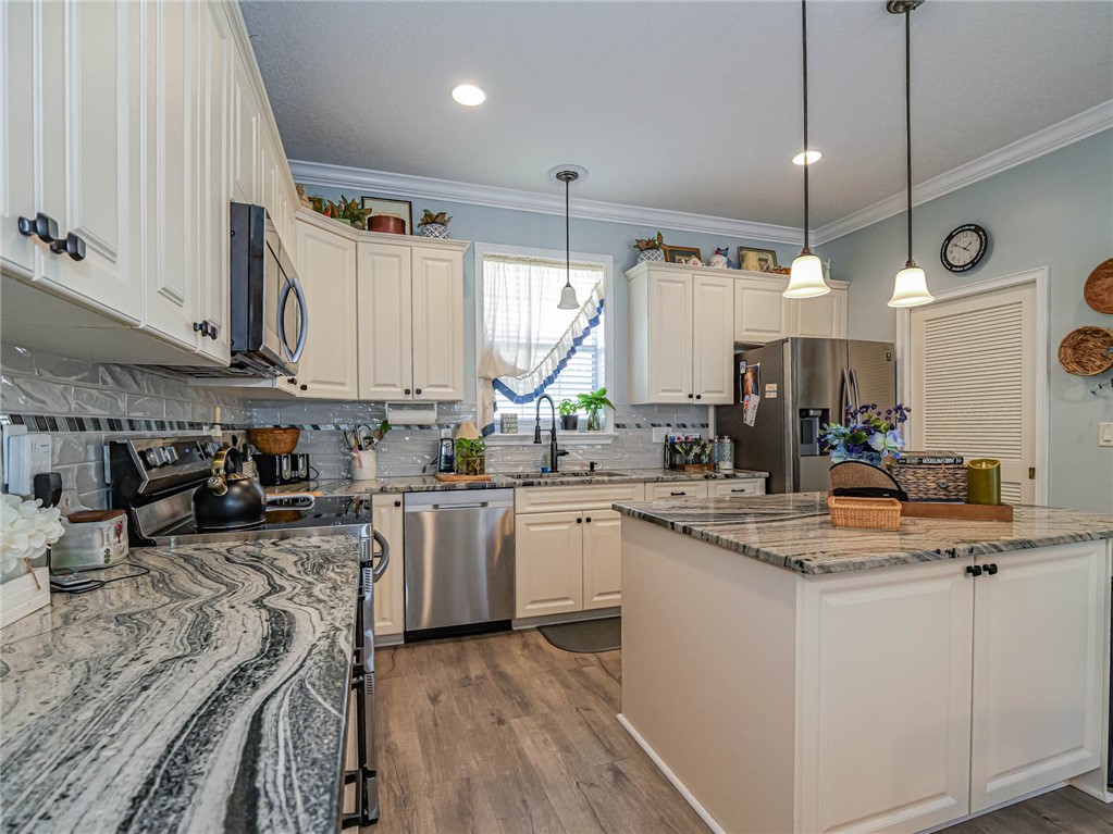 5824 Pine Ridge Circle Vero Beach, FL 32967 - Photo 10 of 34 a kitchen with kitchen island granite countertop a sink cabinets and wooden floor