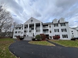 1830 Main Street, Unit 21 Tewksbury, MA 01876 - Photo 1 of 15 a front view of a building with a garden and plants