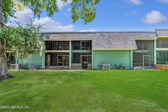 a view of a brick house with a big yard and large trees
