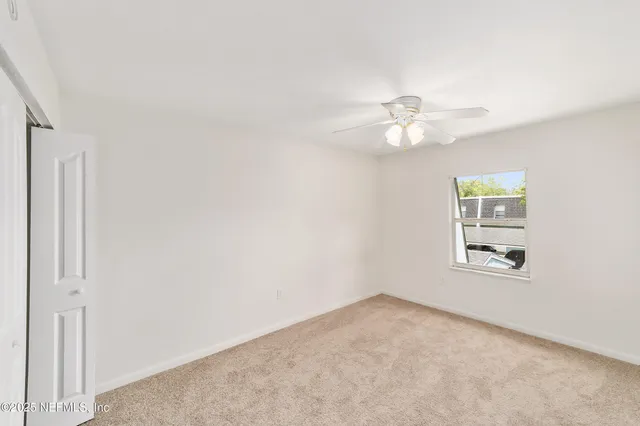an empty room with a window and a ceiling fan