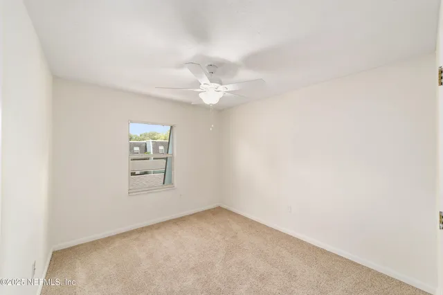 an empty room with a ceiling fan and a window