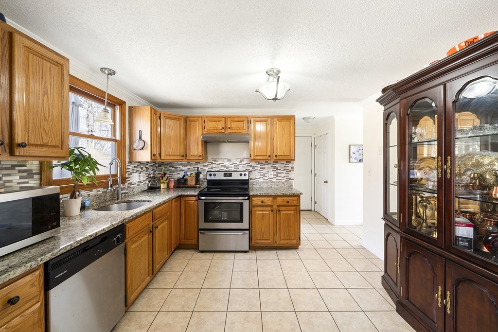 7 Overlook Avenue Haverhill, MA 01832 - Photo 11 of 32 a large kitchen with granite countertop a stove top oven a sink dishwasher a dining table and chairs with wooden floor