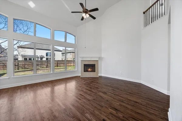 a view of an empty room with wooden floor fireplace and a window
