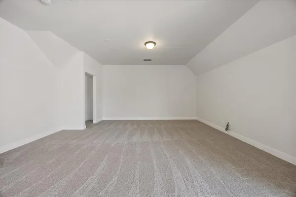 a view of an empty room with kitchen and window