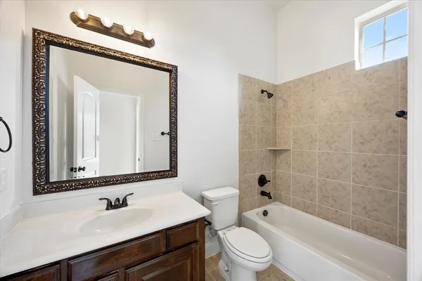 a bathroom with a bathtub shower sink vanity mirror and toilet