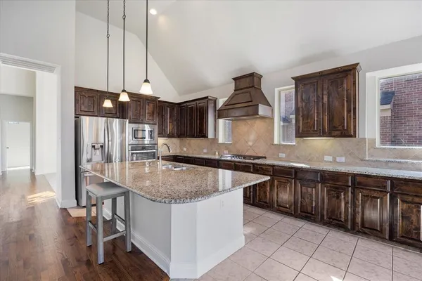 a kitchen with stainless steel appliances granite countertop a sink a stove and a wooden floors