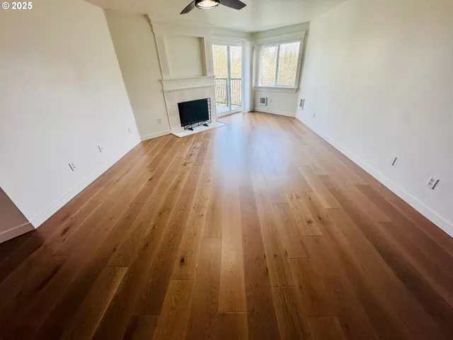 a view of a livingroom with wooden floor a fireplace and windows