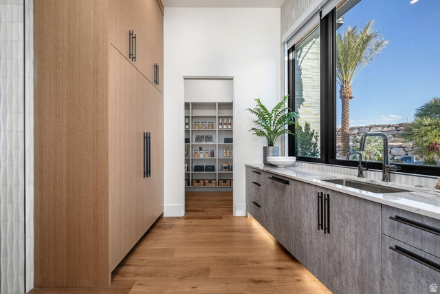 2867 East Granite Way St. George, UT 84790 - Photo 19 of 69 Modern kitchen featuring wood-finish flooring, full-height custom cabinetry, a built-in double sink, a large window, and a walk-in pantry with extensive shelving