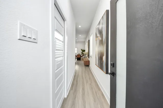 a view of a hallway with wooden floor and a bathroom