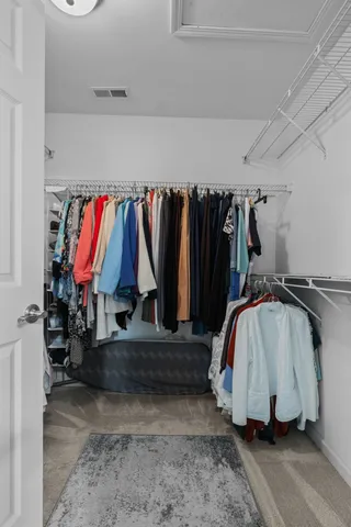 a view of walk in closet with clothes and shoes