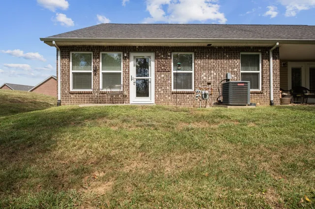 a view of a brick house with large windows and a small yard