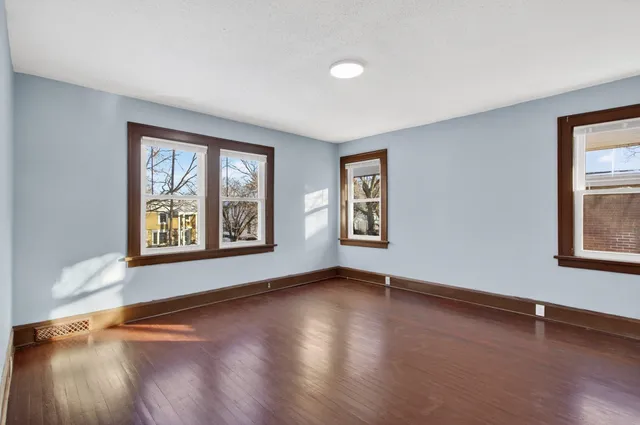 a view of an empty room with window and wooden floor