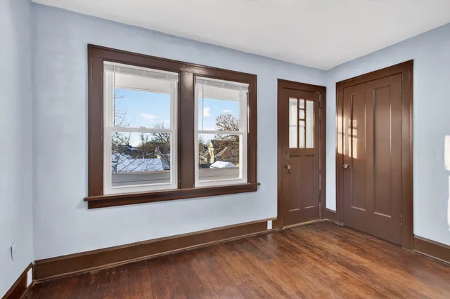 an empty room with wooden floor and windows