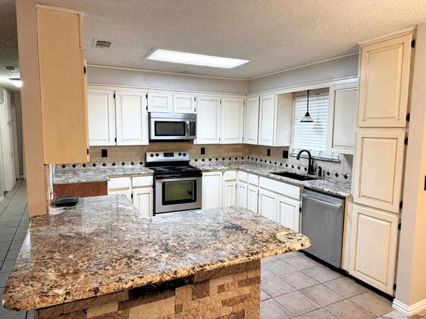 a kitchen with granite countertop a stove sink and refrigerator