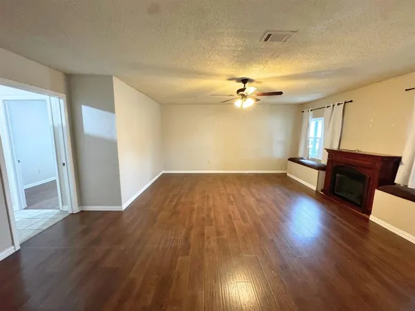 an empty room with wooden floor and fan