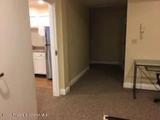 a view of a hallway with wooden floor and a bathroom
