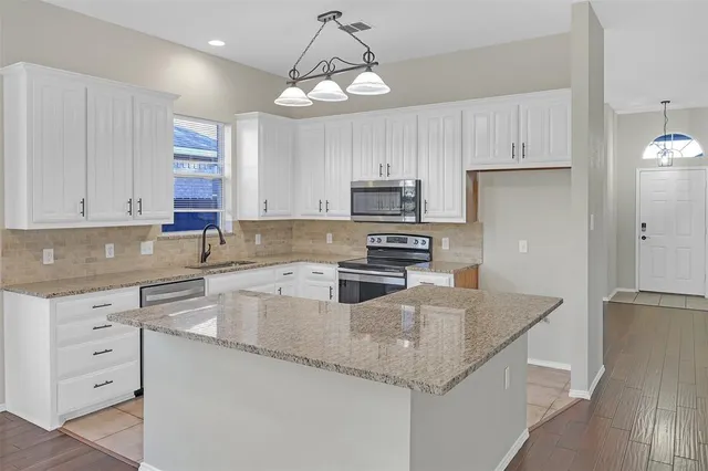 a kitchen with stainless steel appliances granite countertop a sink a stove and a refrigerator