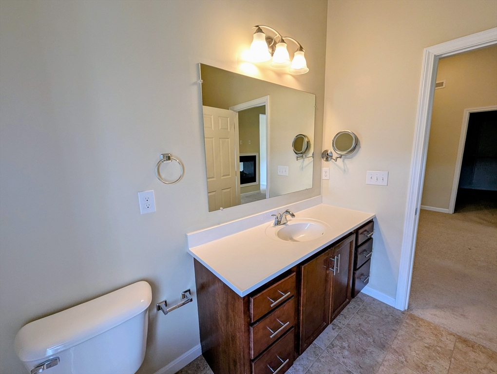 391 America Boulevard, Unit 391 Ashland, MA 01721 - Photo 16 of 22 a bathroom with a toilet sink and mirror