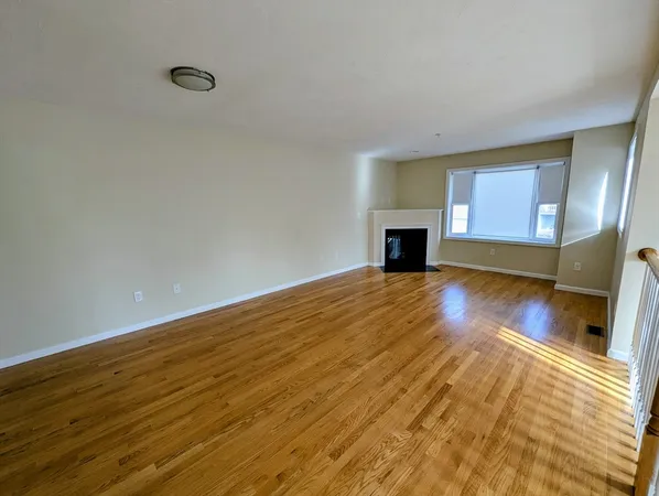 a view of a room with wooden floor fireplace and windows