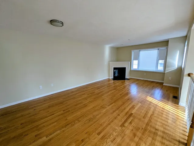 a view of a room with wooden floor fireplace and windows