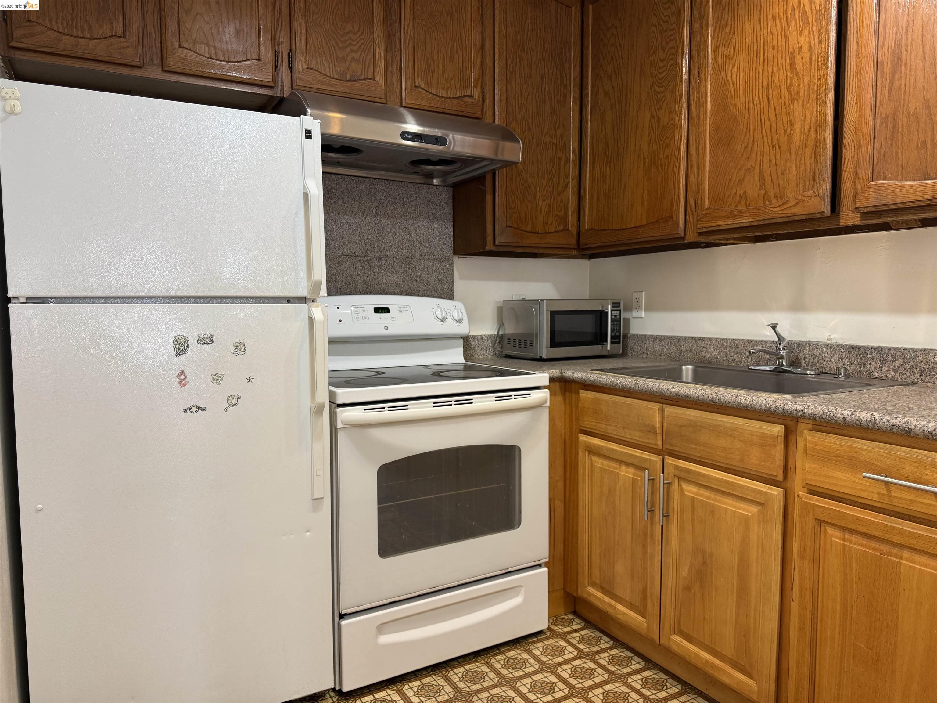 330 8th Street, Unit 3D Oakland, CA 94607 - Photo 4 of 13 Kitchen with white appliances and wood finish cabinetry