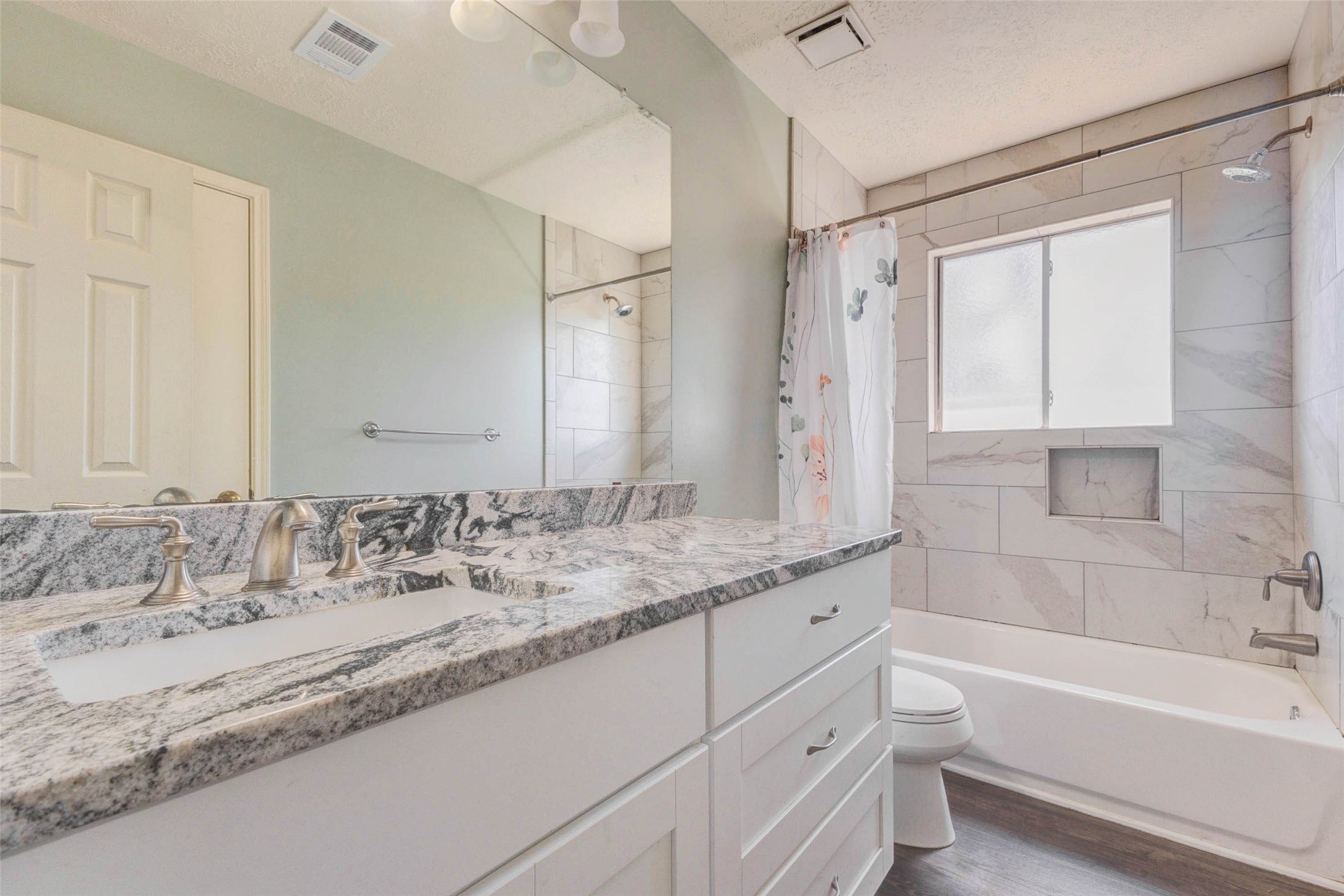 9215 Landry Boulevard Spring, TX 77379 - Photo 32 of 42 The guest bathroom showcases a clean and timeless design with granite countertops, white cabinetry, and an updated tub and shower combination featuring tile that extends to the ceiling.
