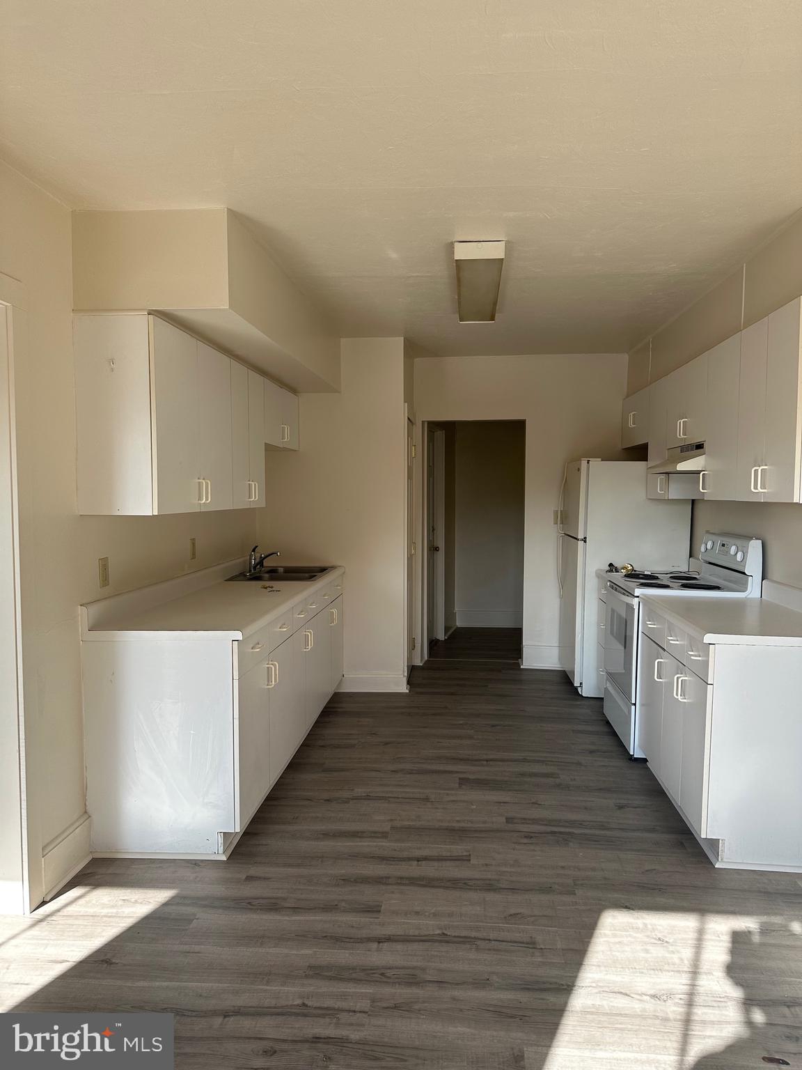 a large kitchen with a white stove top oven and white cabinets