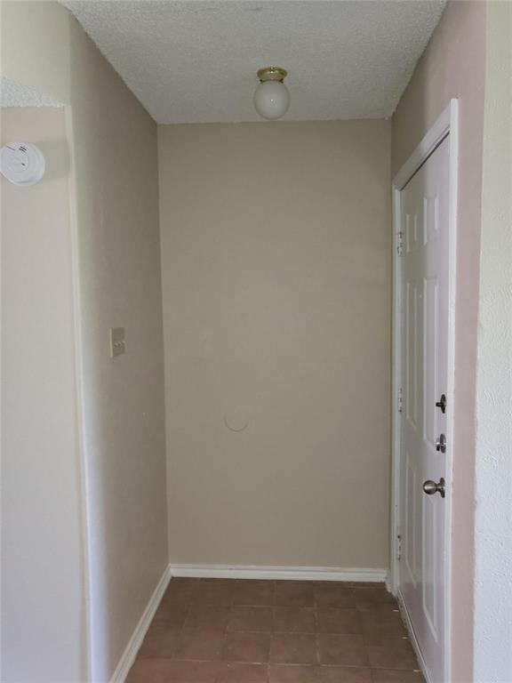 8005 Rothington Road, Unit 57 Dallas, TX 75227 - Photo 13 of 15 Hallway with a textured ceiling and tile patterned floors